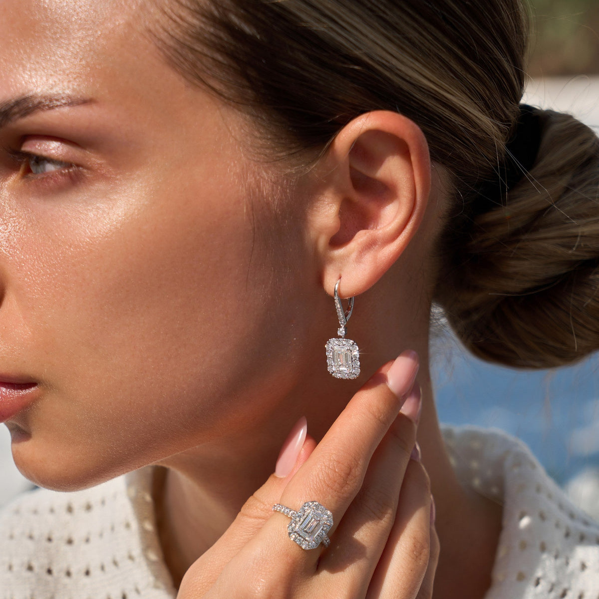 Close up of a woman wearing diamond earrings and ring outdoors