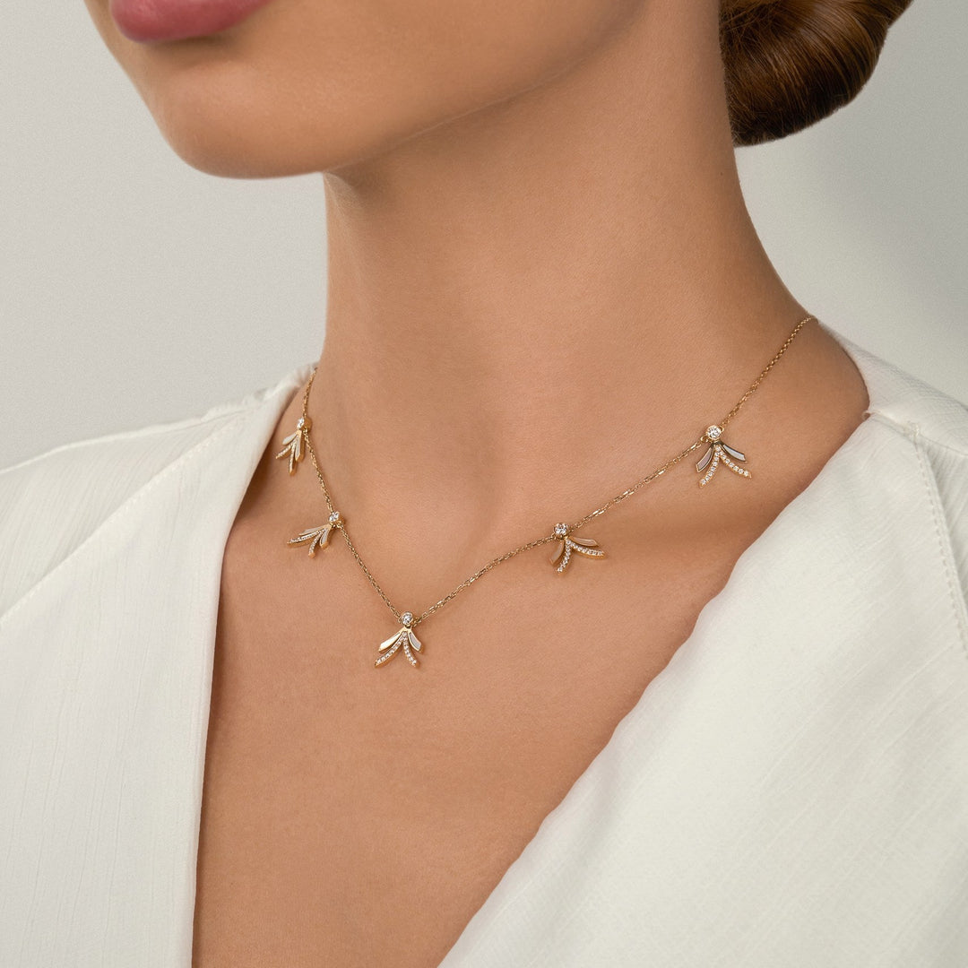 Necklace with small pendants worn by a person against a neutral background