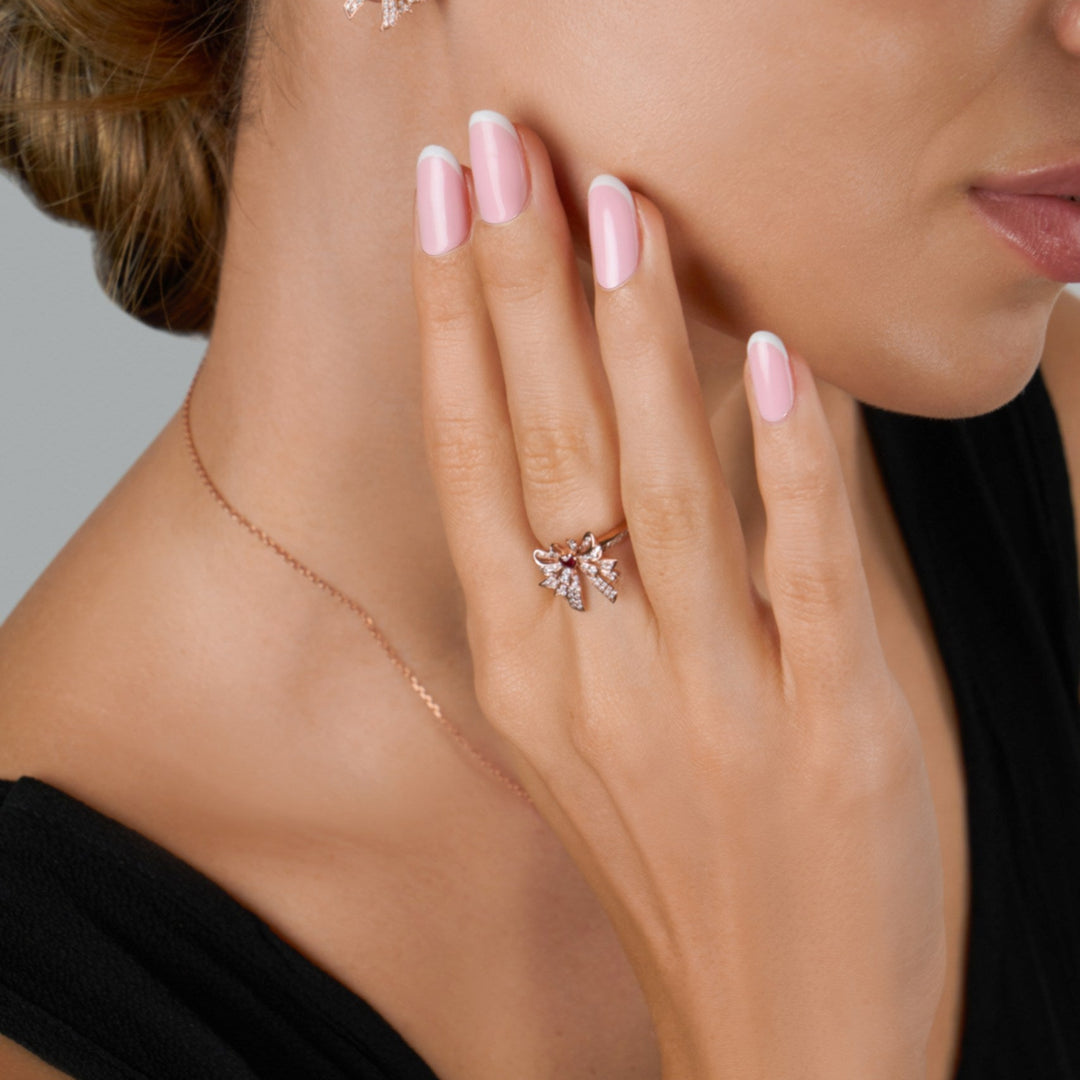 Close-up of a woman wearing diamond earrings and ring with a neutral background